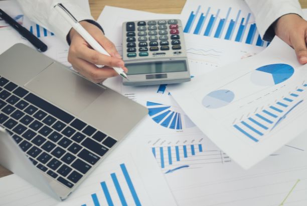 ALT: Persona revisando un balance contable en un escritorio con calculadora y portátil